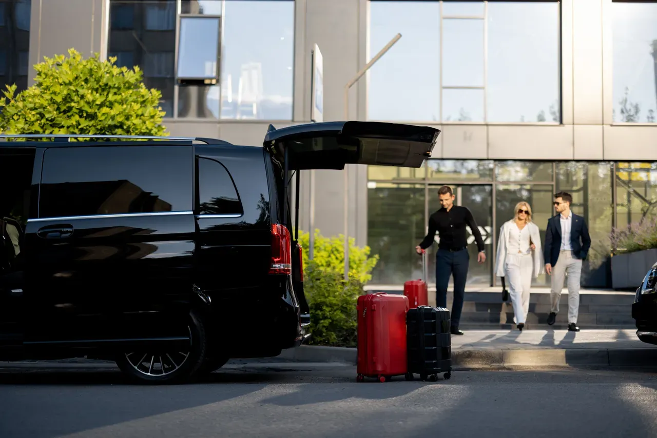 Chauffeur Houci Transport aidant des clients à porter leurs bagages pour un transfert aéroport