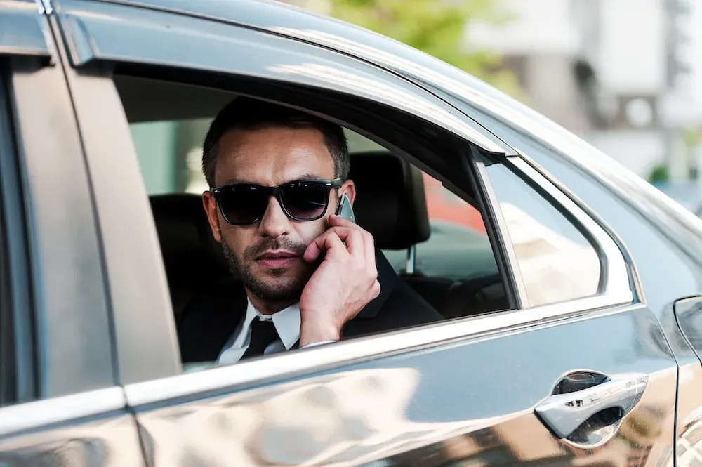 Homme d'affaires au téléphone à l'arrière d'une berline avec chauffeur à Bordeaux